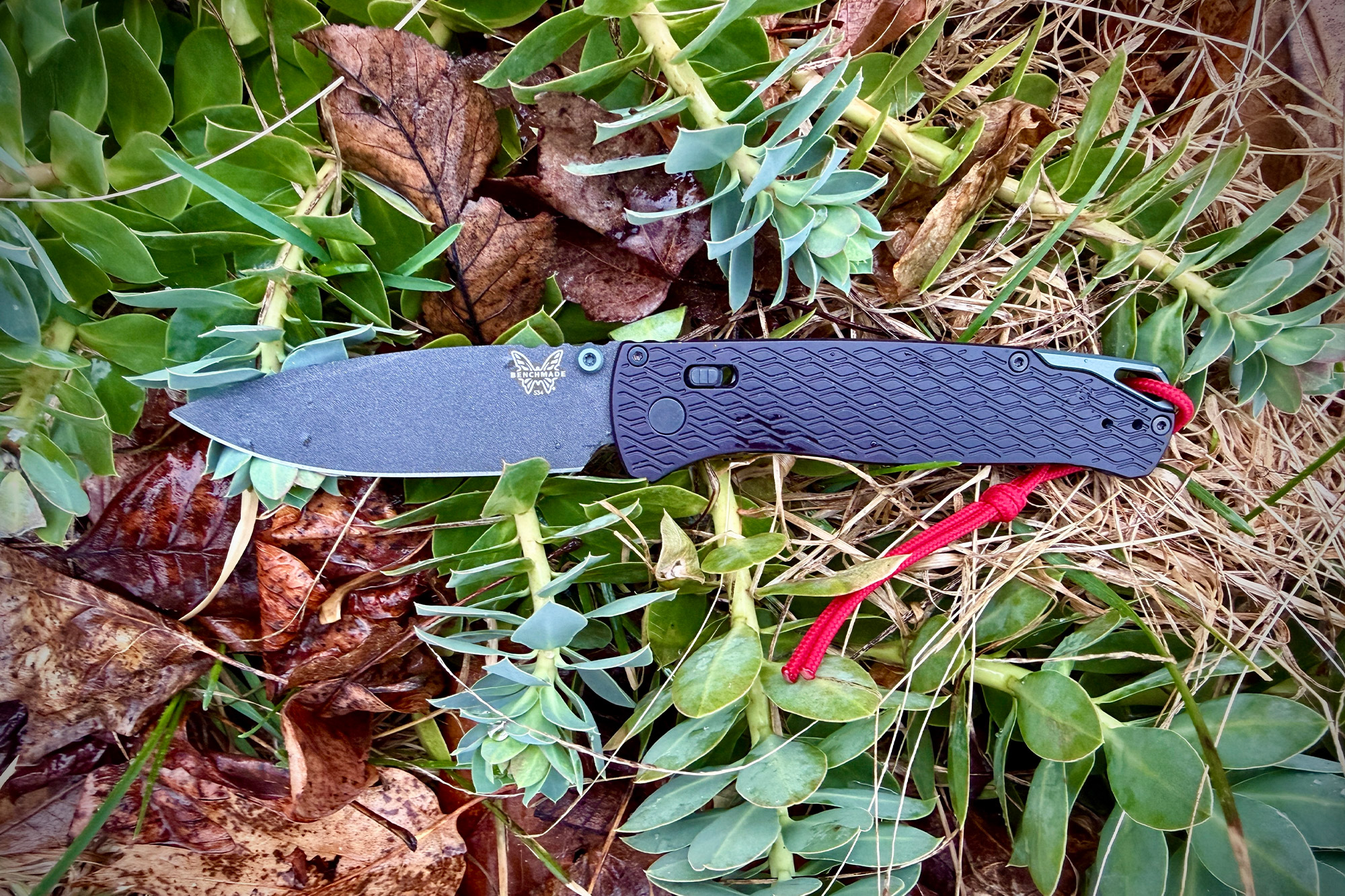 Benchmade Bugout Vapyr placed on plants and leaves in garden setting