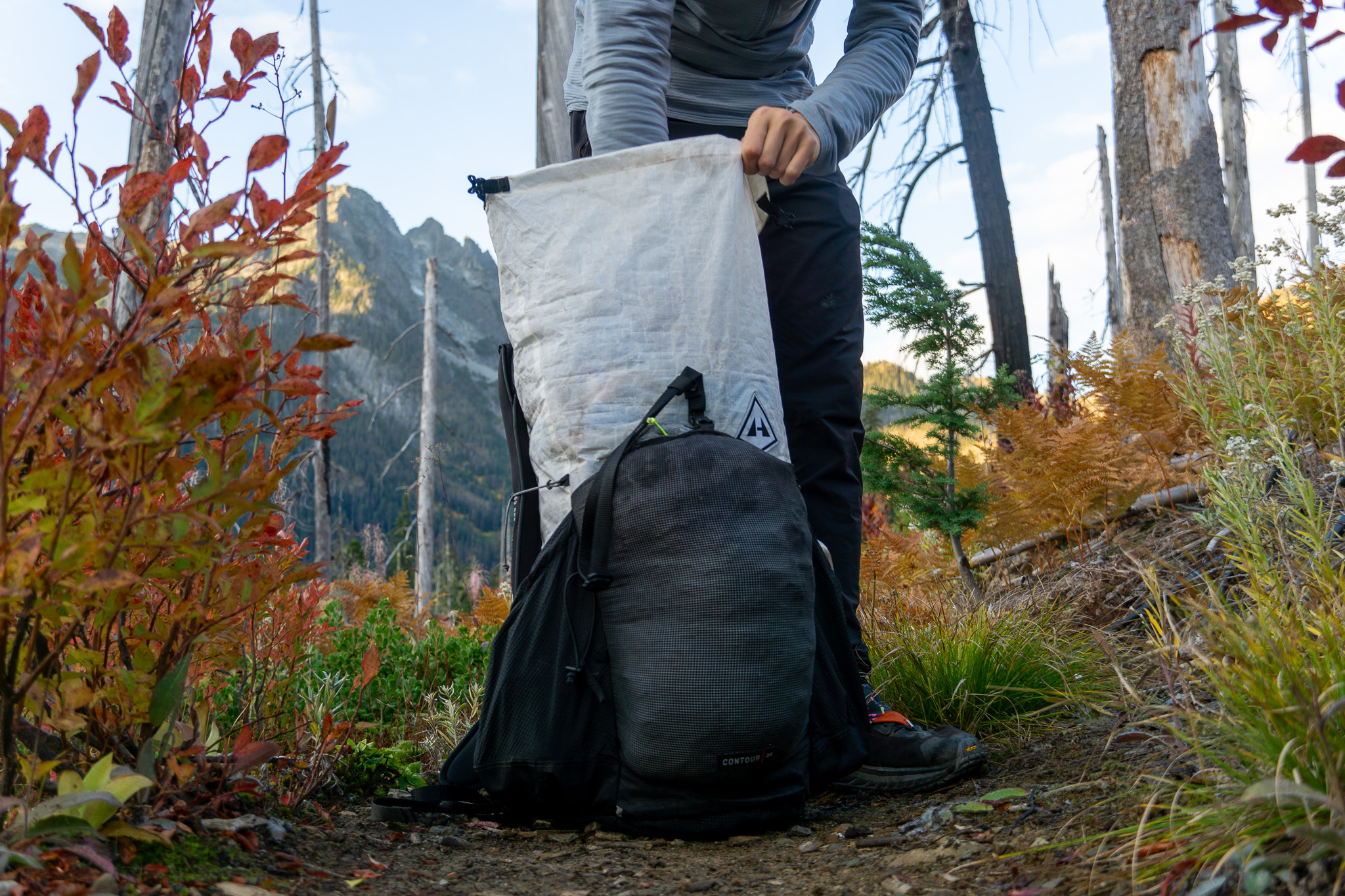 a gearjunkie tester reaches into a hyperlite mountain gear contour pack in the north cascades during autumn
