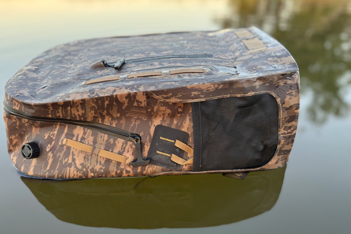 Waterproof backpack floating partially submerged, showing sealed seams and side pocket