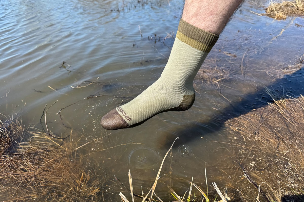 Cross Point Gear Mountain Socks held above shallow water near the shoreline