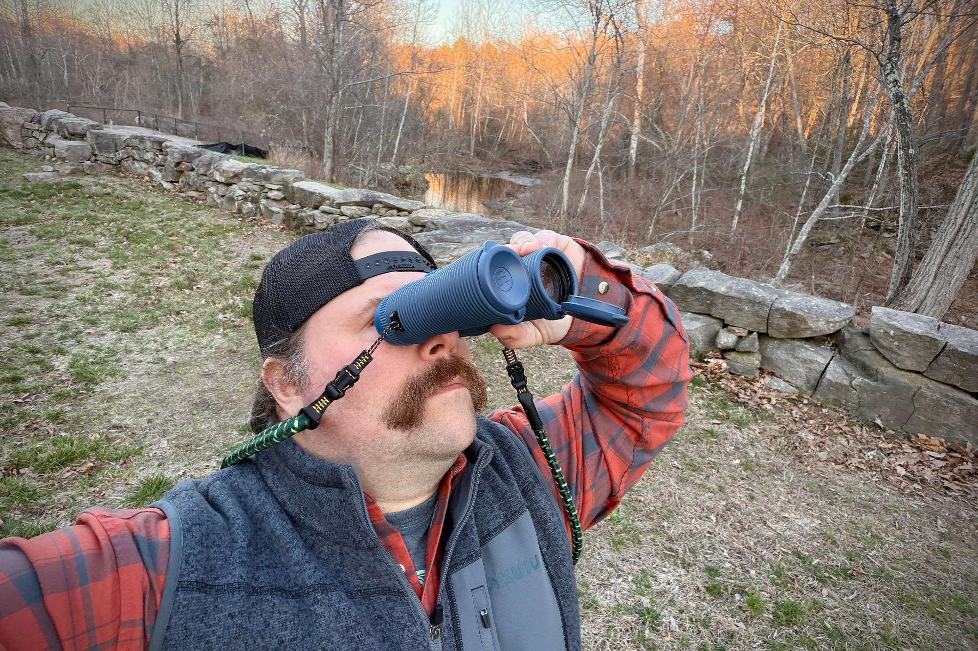 Field Issue binoculars used one handed while looking across an outdoor landscape