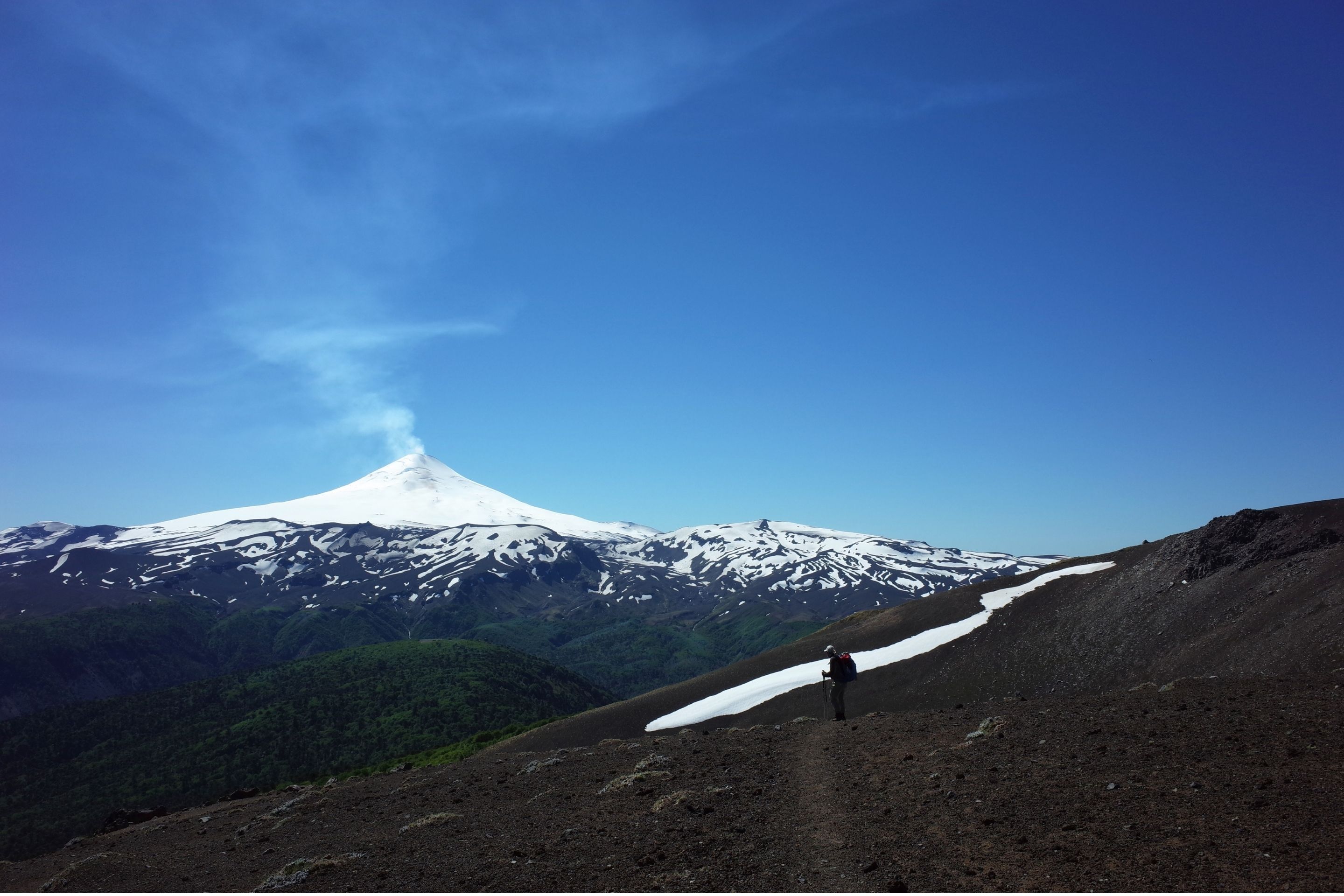 hiker in front of a volcano