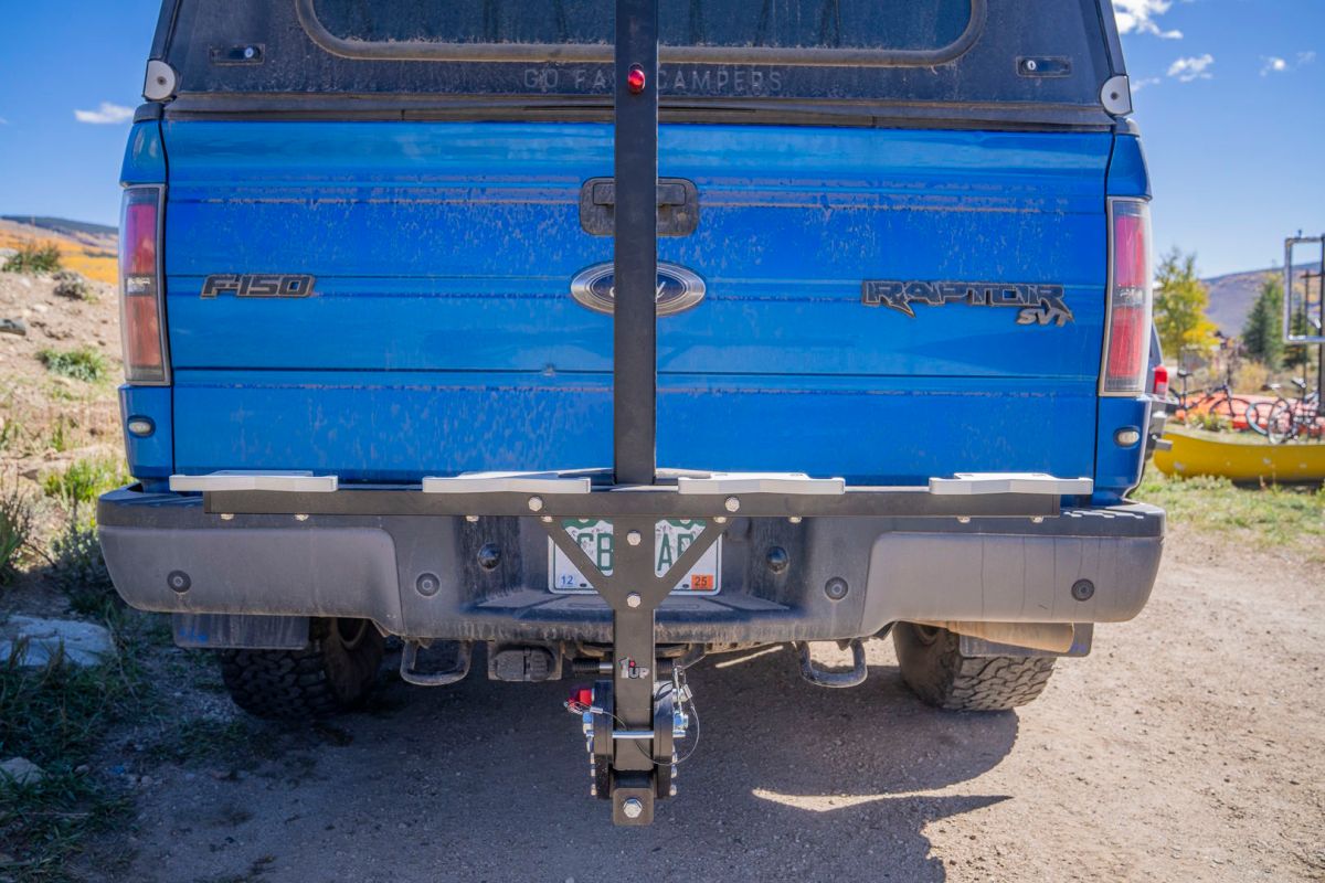A rear-mounted bike rack attached to a blue pickup truck.