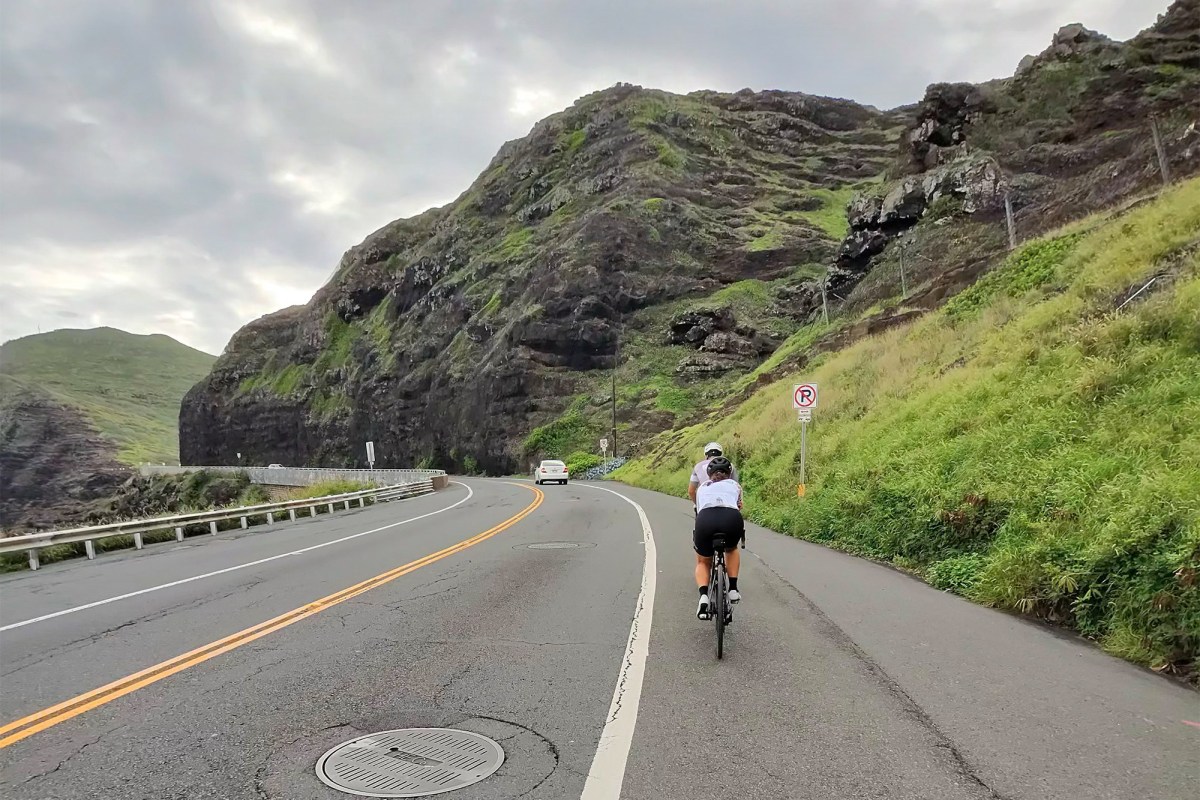 Cyclist riding on a road while wearing Oakley Meta Vanguard glasses