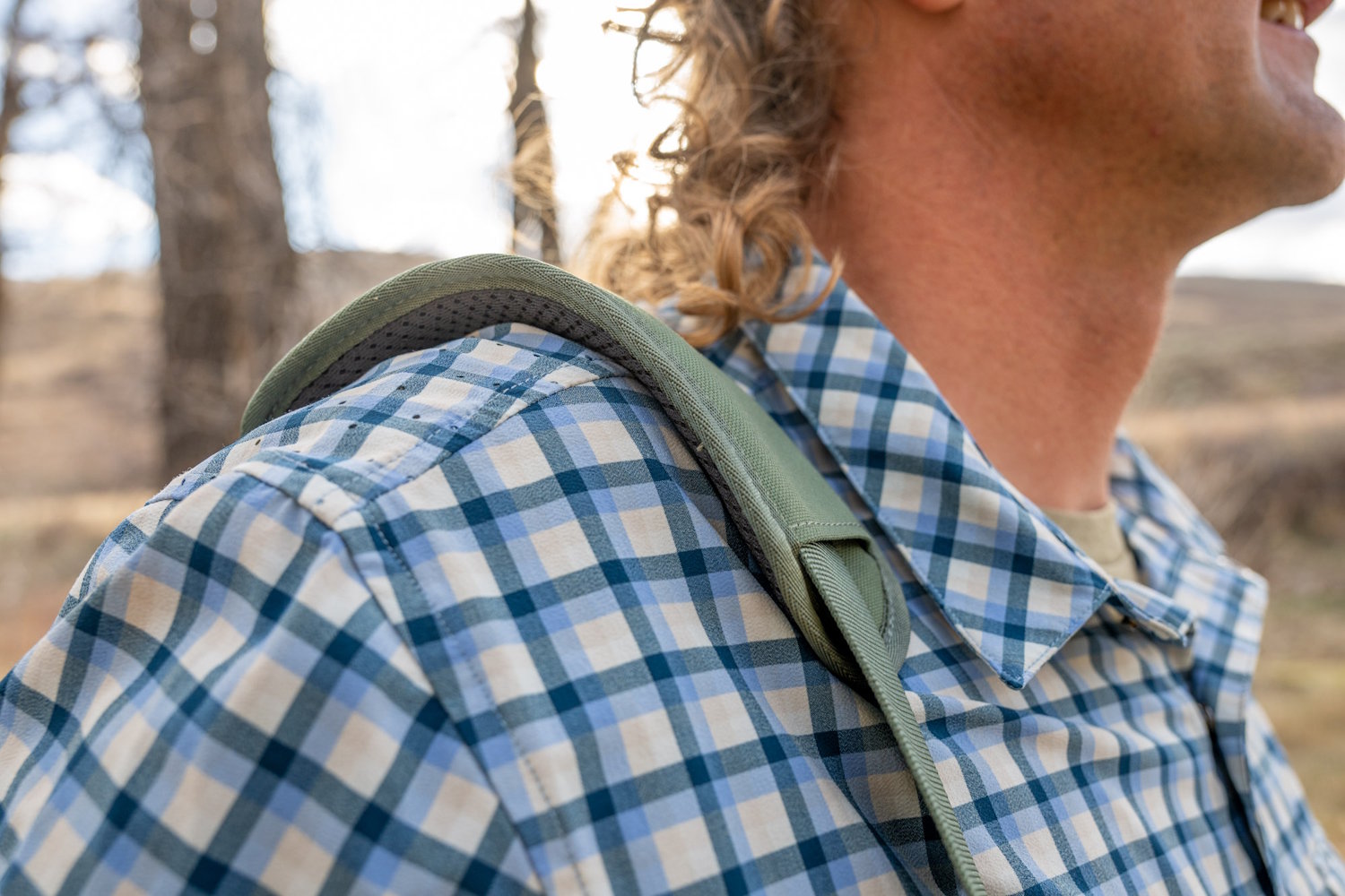 A close-up view of the green padded shoulder strap of the REI Trail Gate cooler resting on a person's shoulder