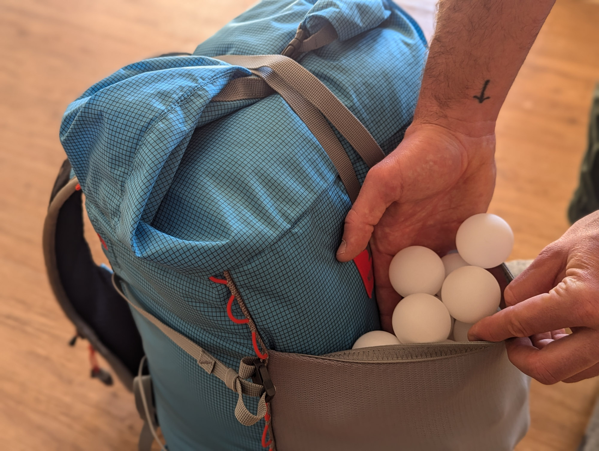 a gearjunkie tester using ping pong balls to measure the volume of an external pocket on an ultralight backpack