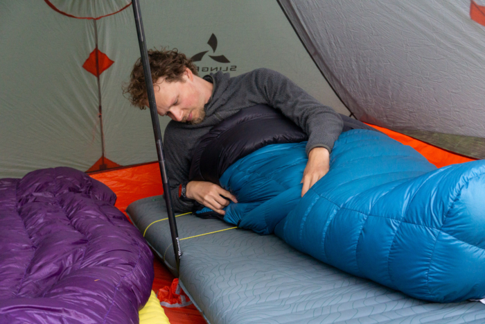 gearjunkie tester nick belcaster adjusts the sleeping pad straps on the katabatic alsek sleeping quilt while backpacking in Washington state