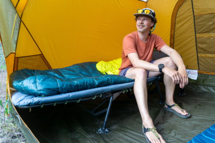 gearjunkie tester nick belcaster sits on the rei wonderland comfort cot during testing in washington state