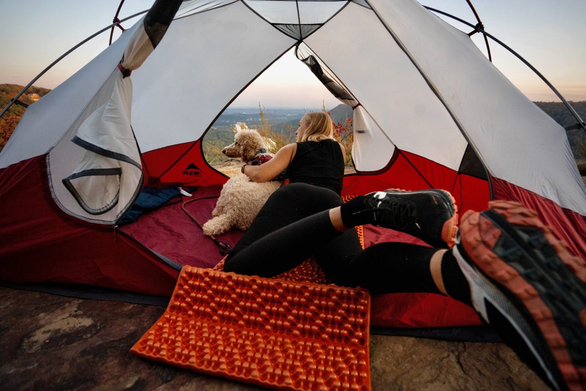 gearjunkie tester lays on a nemo switchback foam sleeping pad with a poodle beside her, all inside a tent