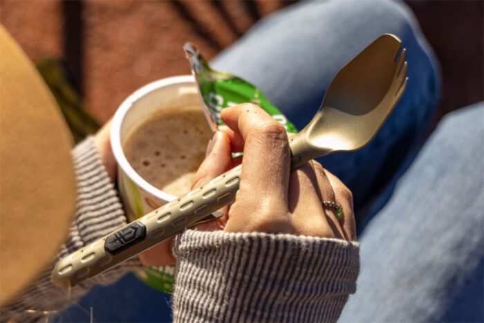 person opening hot cereal cup while holding a Gerber spork
