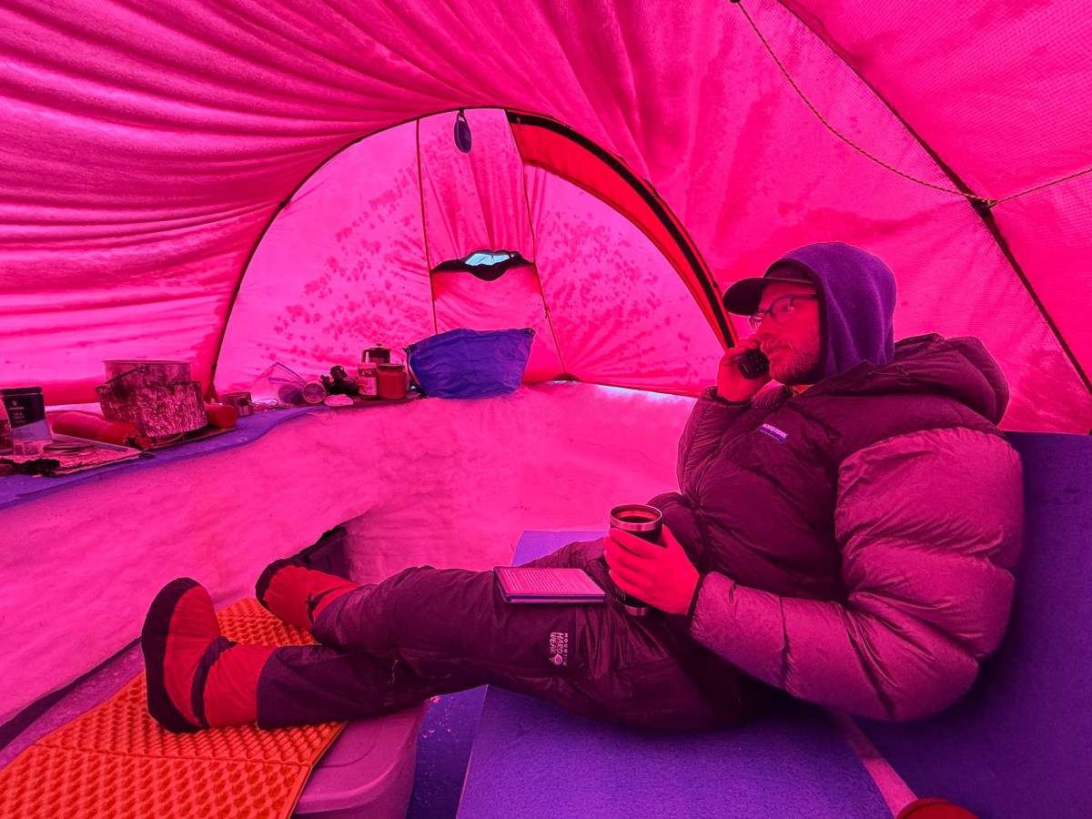 climber talks on a satellite phone in tent on denali