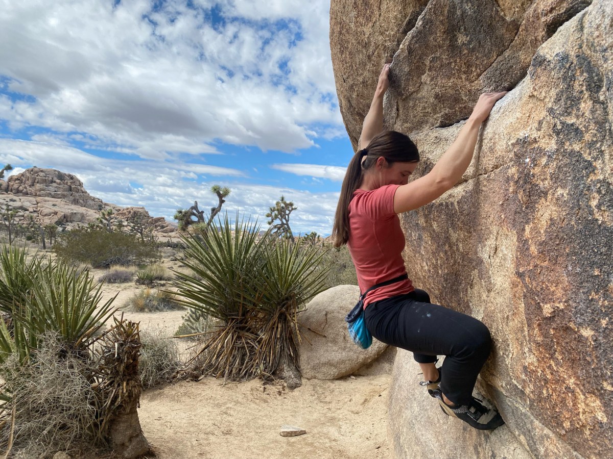 tester katie griffith boulders in joshua tree national park while wearing a merino wool t shirt and test mobility and fit