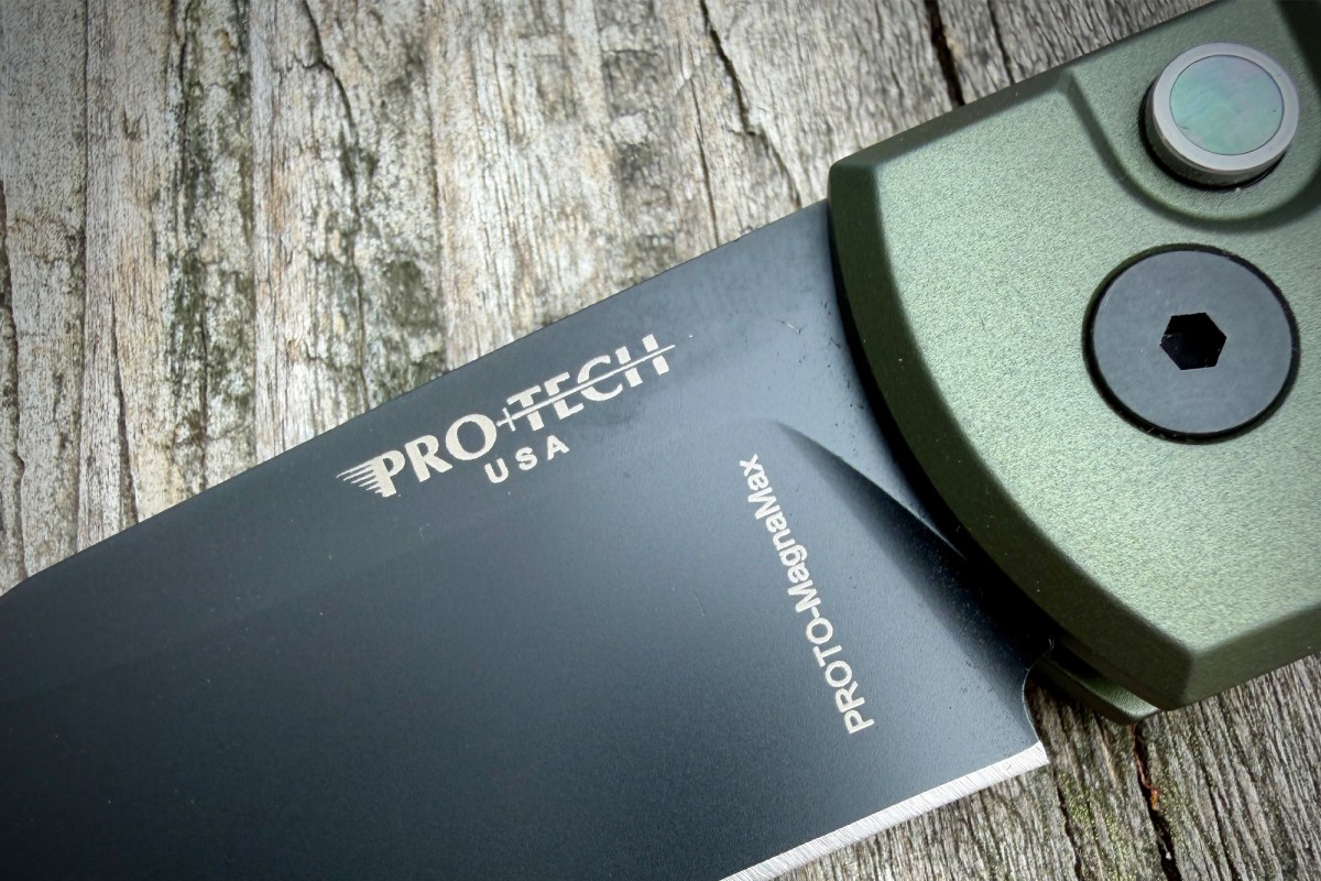 Close-up of the Scapegoat Compact knife blade, pivot button, and green handle detail
