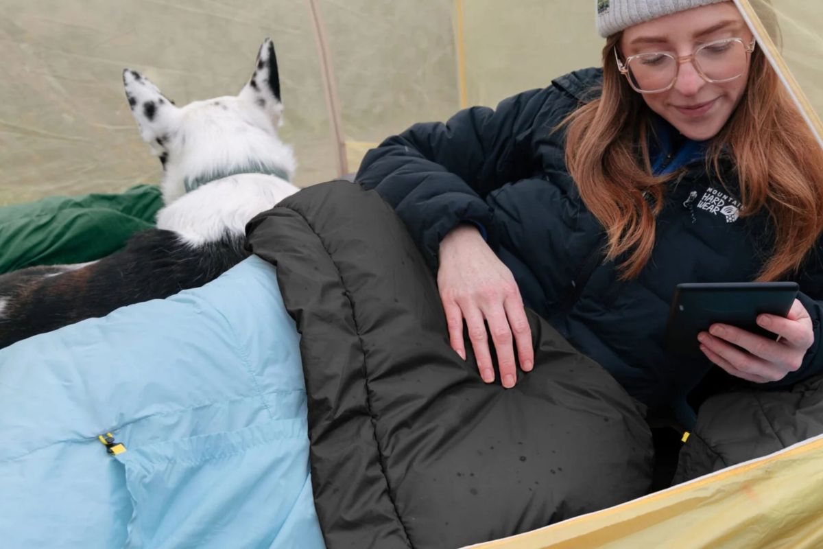 person sits in tent with sleeping bag