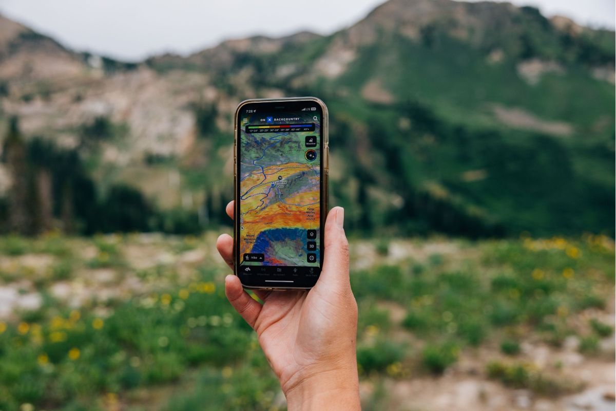 person holds up phone in mountains with a map on it