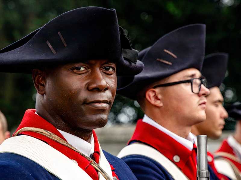An Old Guard soldier in Revolutionary War-era uniform stands during Lexington’s 250th anniversary commemoration.