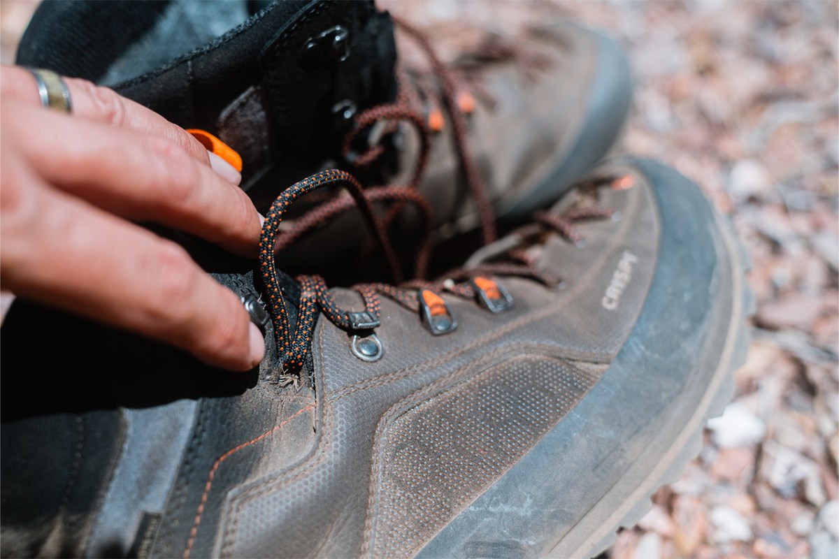 Close view of a hand adjusting the laces on a Crispi hunting boot