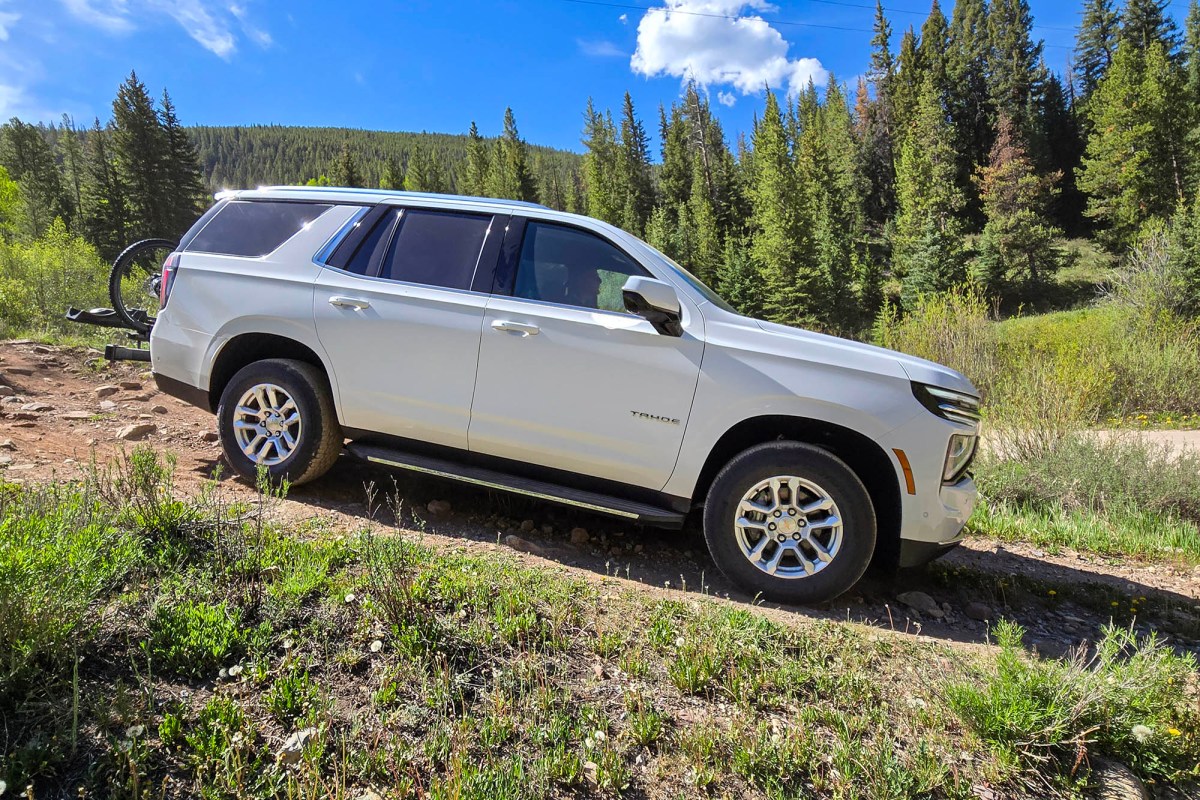 White Chevrolet Tahoe driving off-road near a forest trail