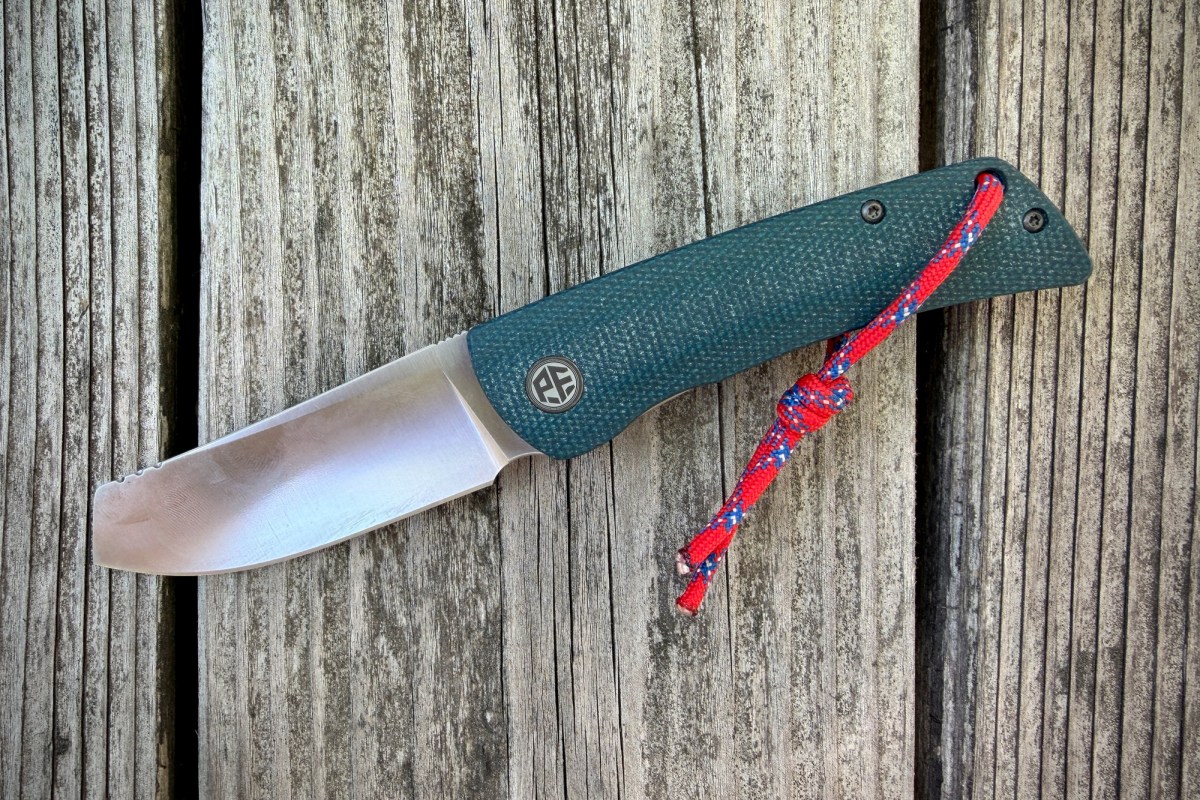 Open Flavorist knife with teal handle and red lanyard on weathered wood
