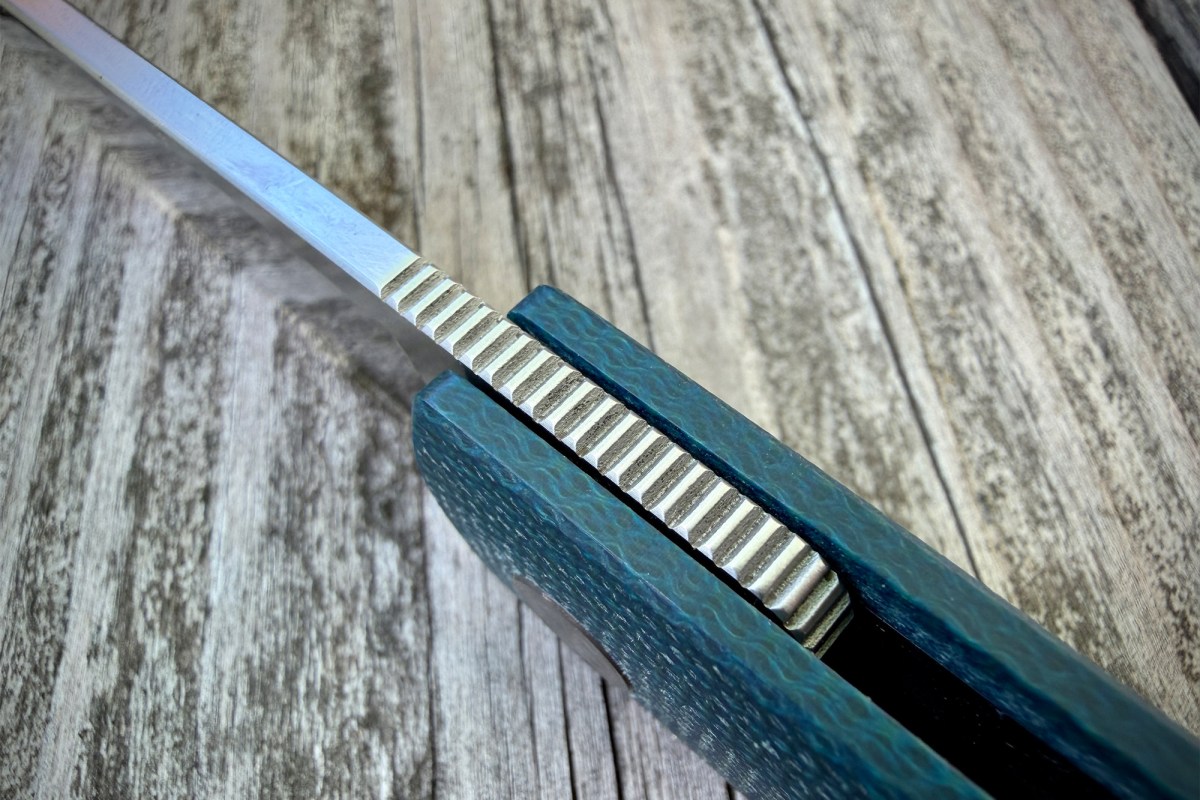 Close-up of the Flavorist knife spine and textured teal handle on wood