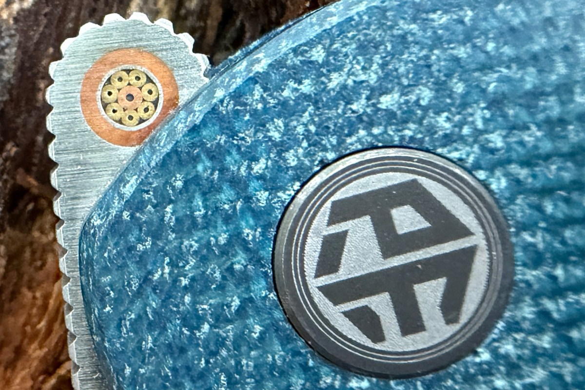 Close-up of the Flavorist thumb stud, pivot logo, and blue textured handle