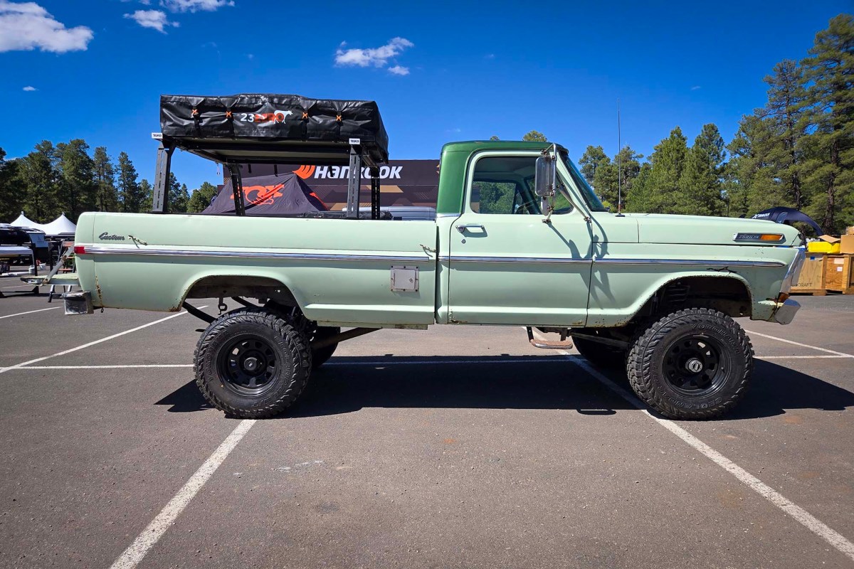 Light green Ford F-250 with a rooftop tent mounted over the bed