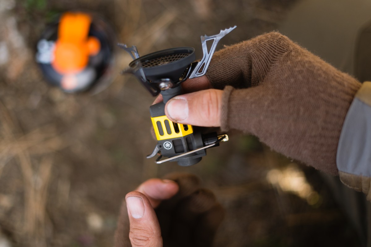 A hand holds the Roughridge stove burner and ignitor