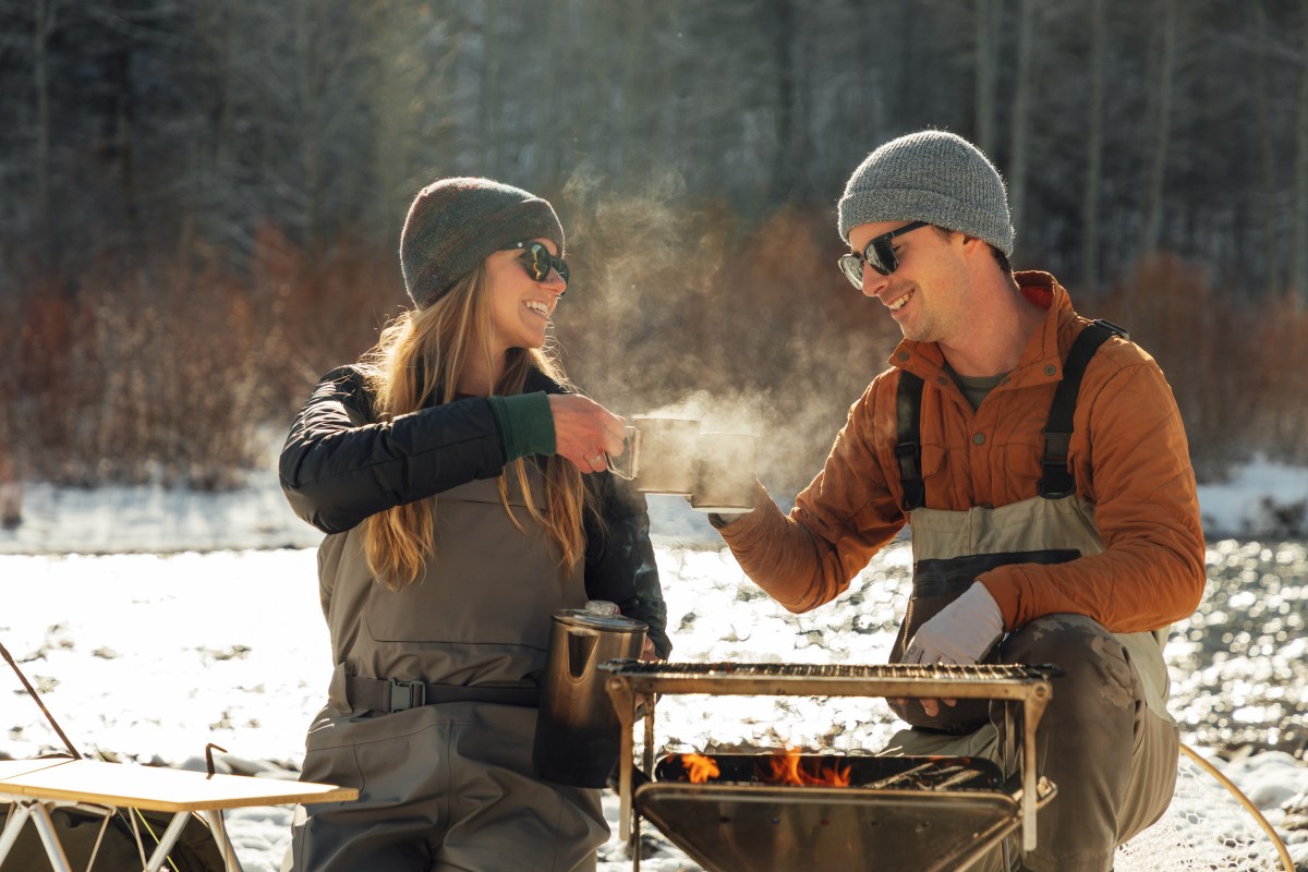 Couple in Overalls Sitting Outdoors Clinking Mugs