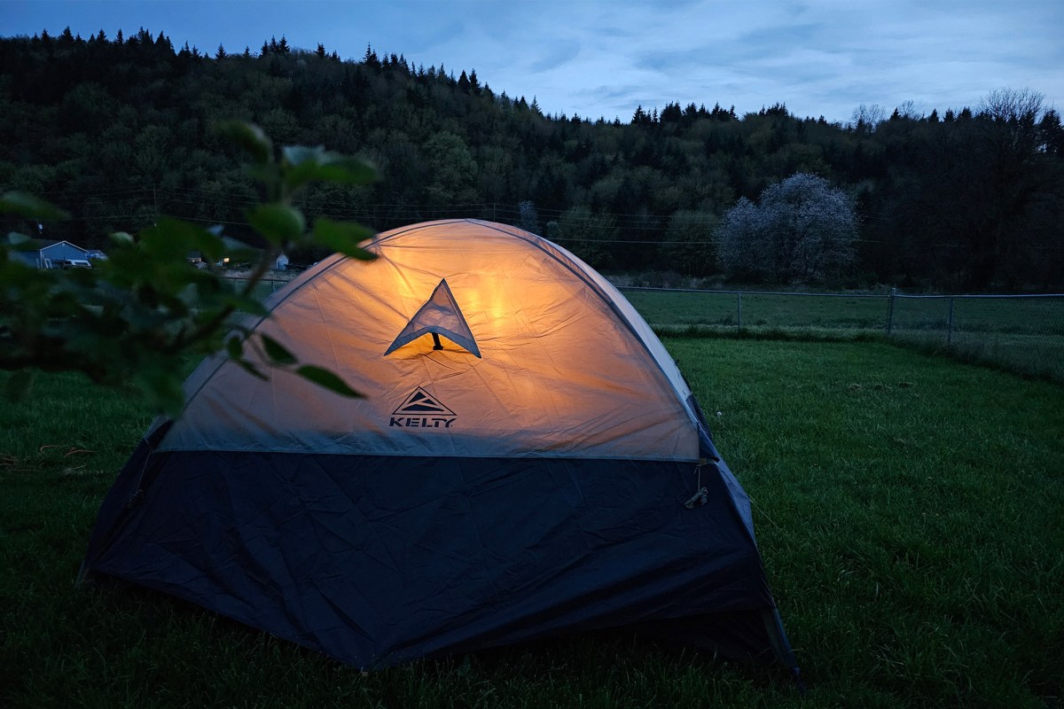 Late Start 4P tent glowing from inside in a grassy campsite at dusk