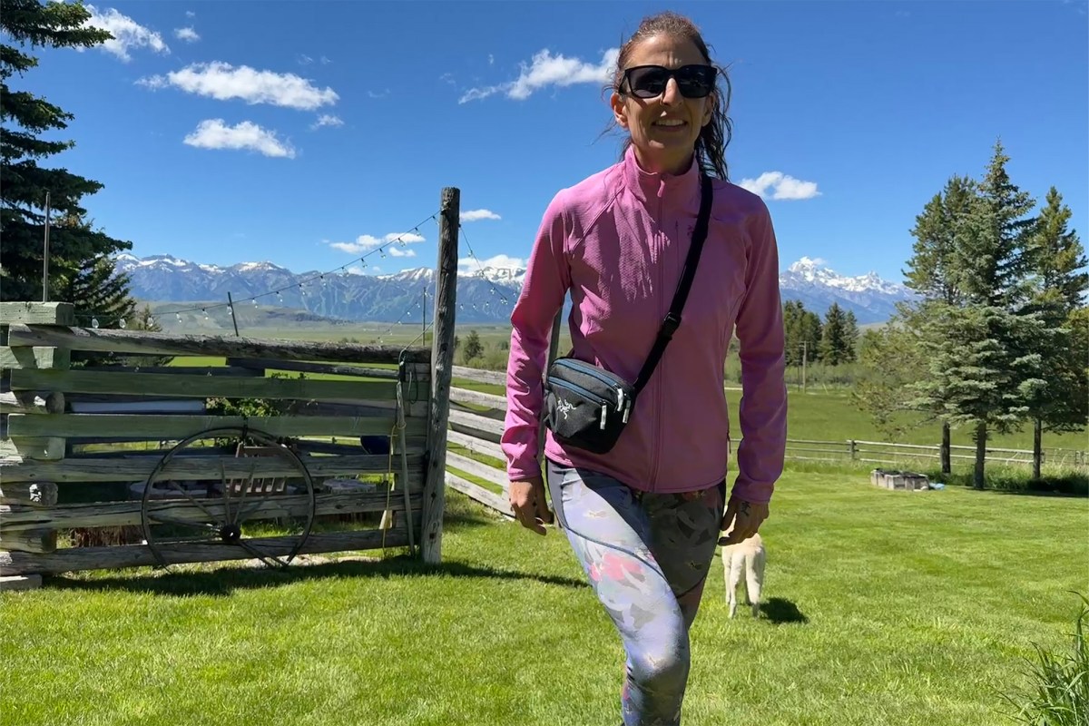 Person wearing a black Arc’teryx waist pack while walking across a grassy yard
