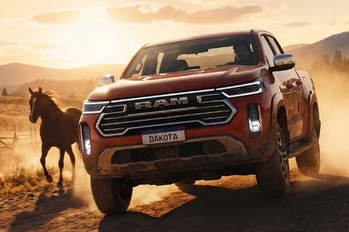 Ram Dakota pickup driving on a dusty road beside a horse at sunset