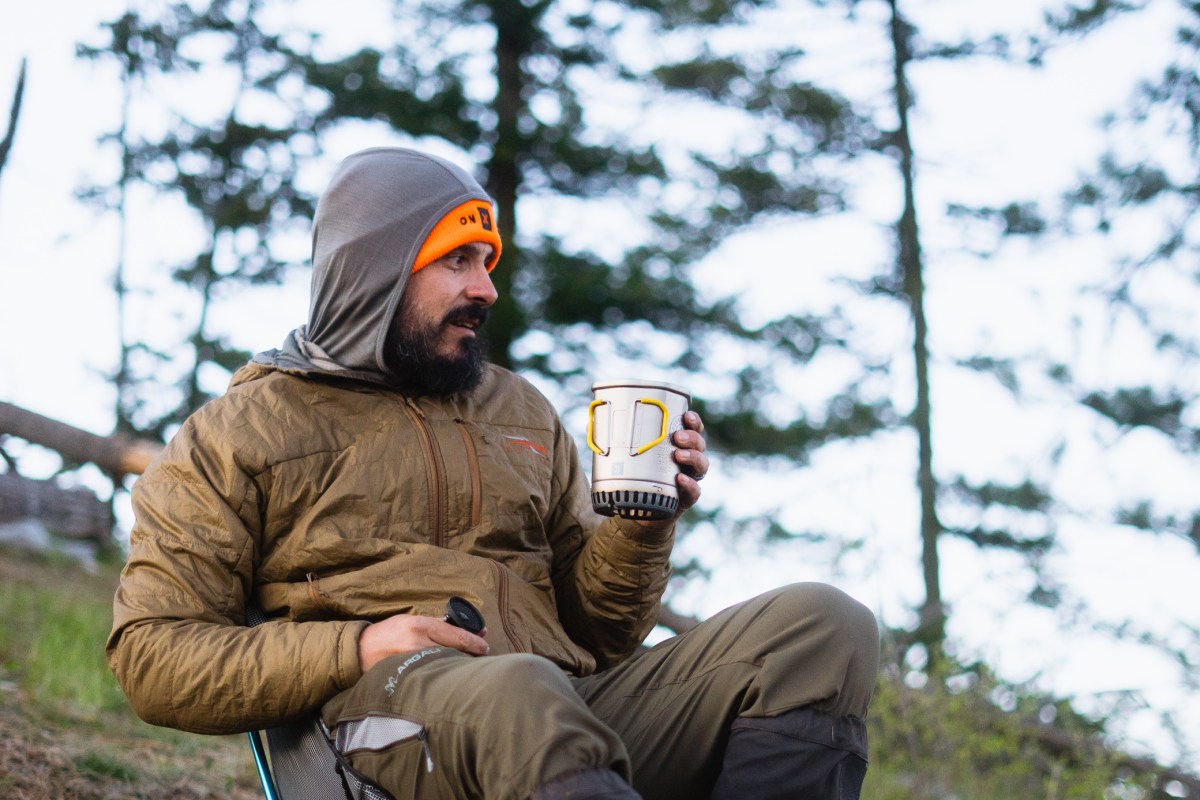 A camper holds the Roughridge Highcountry Cook System while sitting outdoors