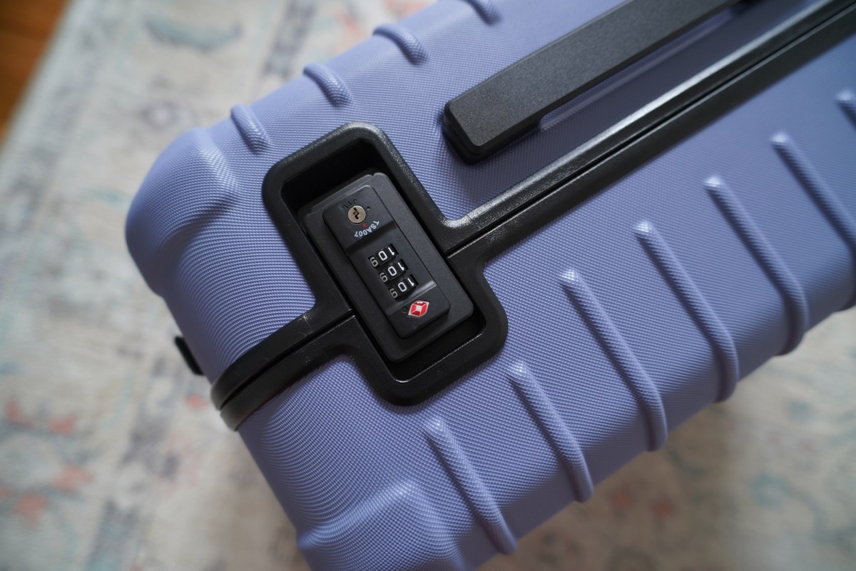 Close-up of the TSA combination lock and black side handle on the hard-sided carry-on luggage