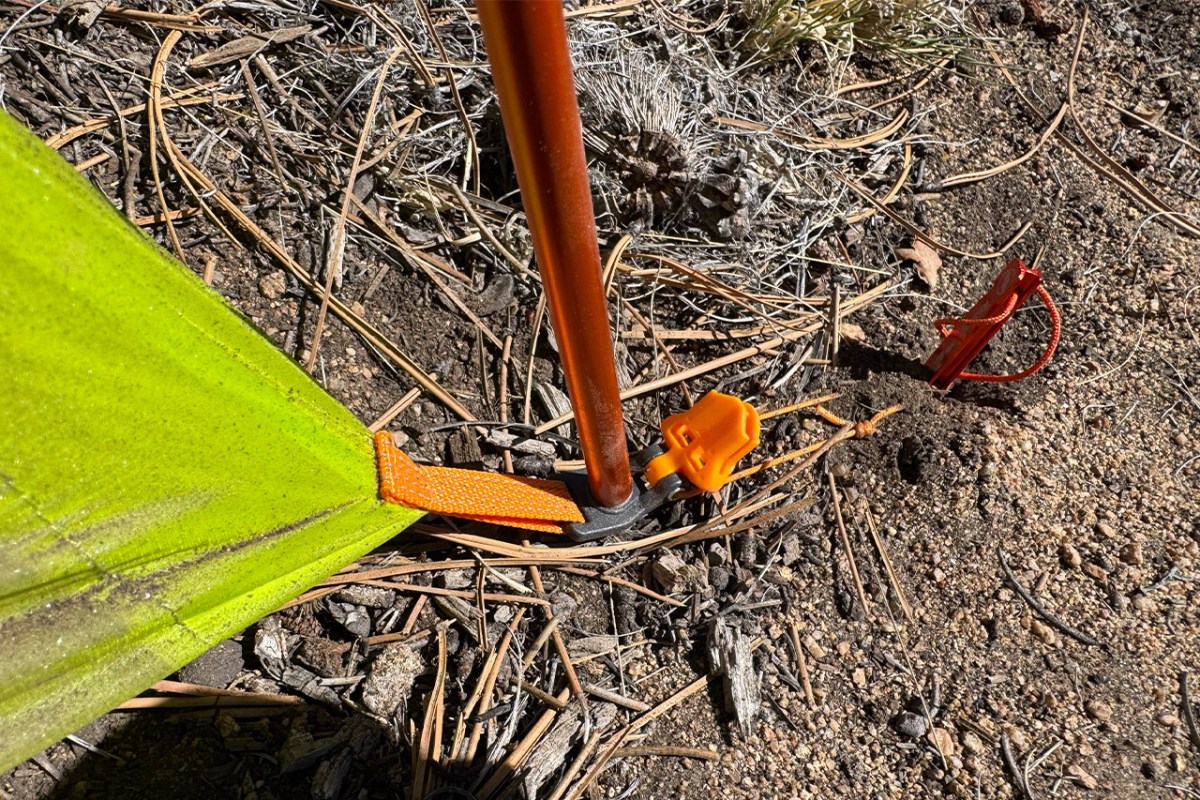 Close view of a Tiger Wall UL2 pole, corner strap, and stake secured in dry ground