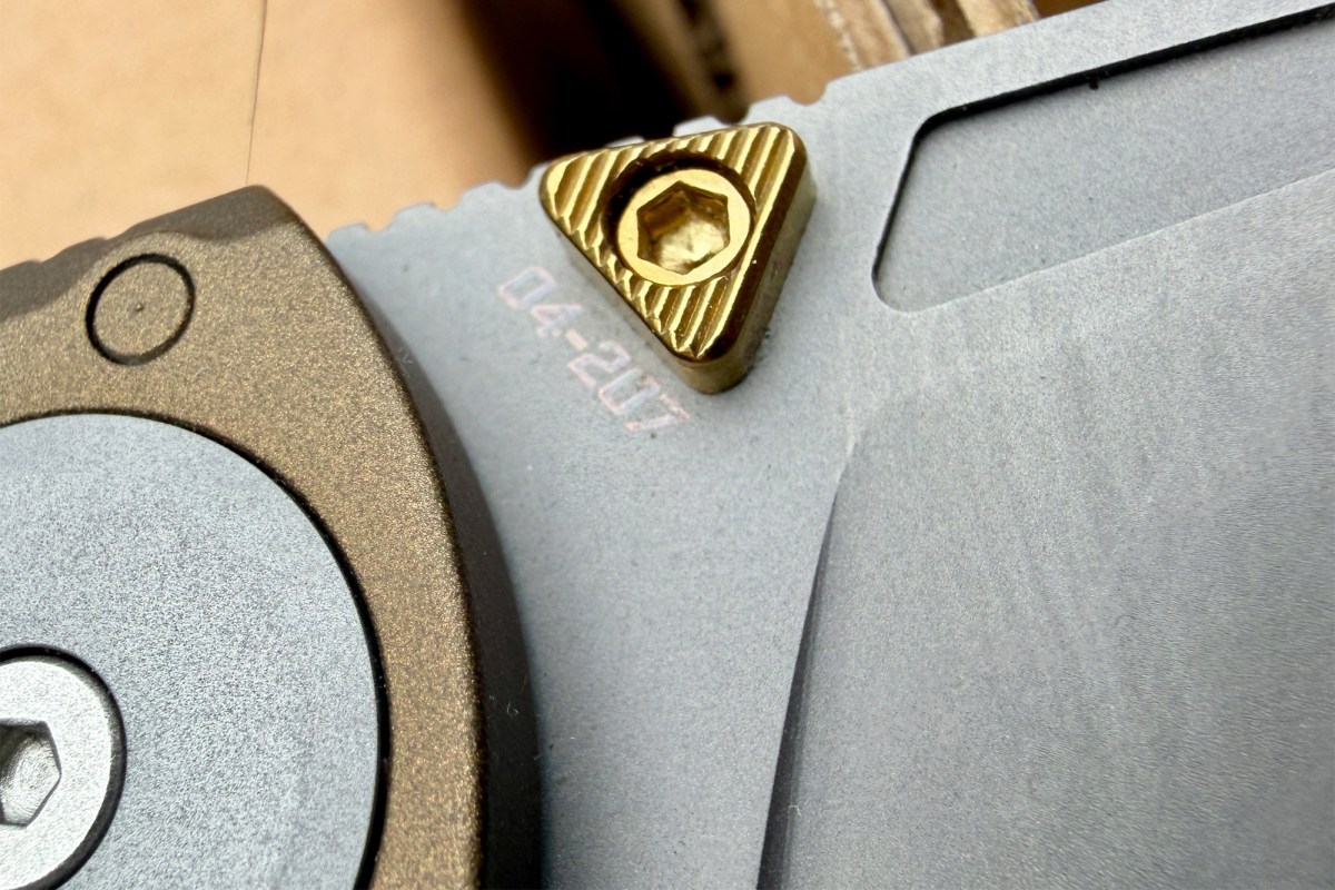 Close-up of the RMX Thumbstud knife’s gold thumb stud and blade detail