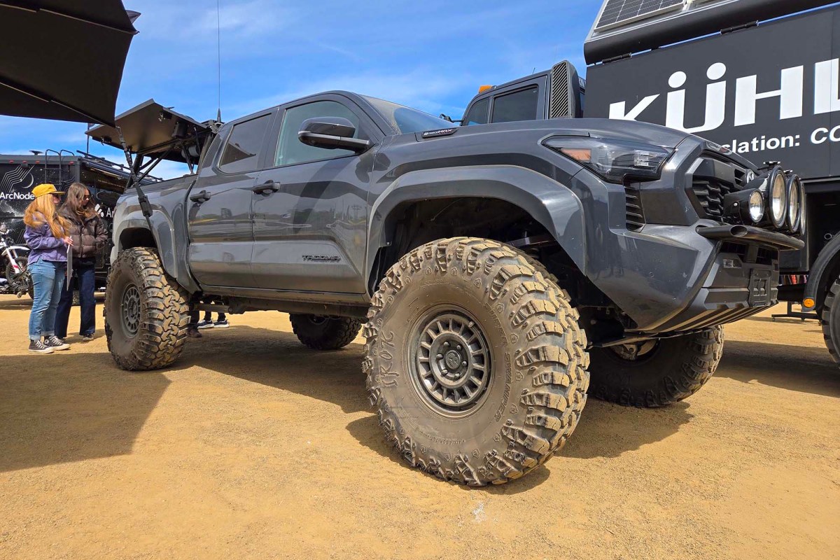 Gray Toyota Tacoma with oversized off-road tires displayed at an outdoor event