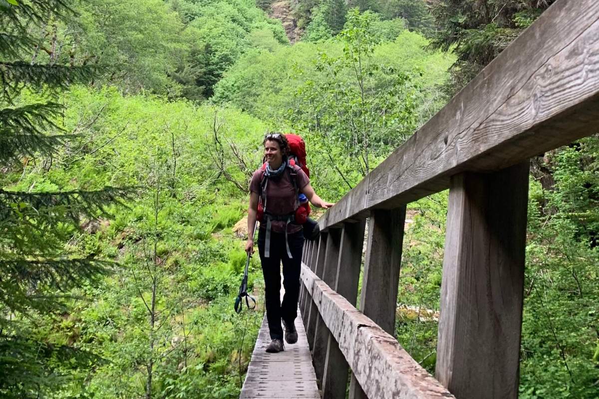backpacker walks across wooden bridge