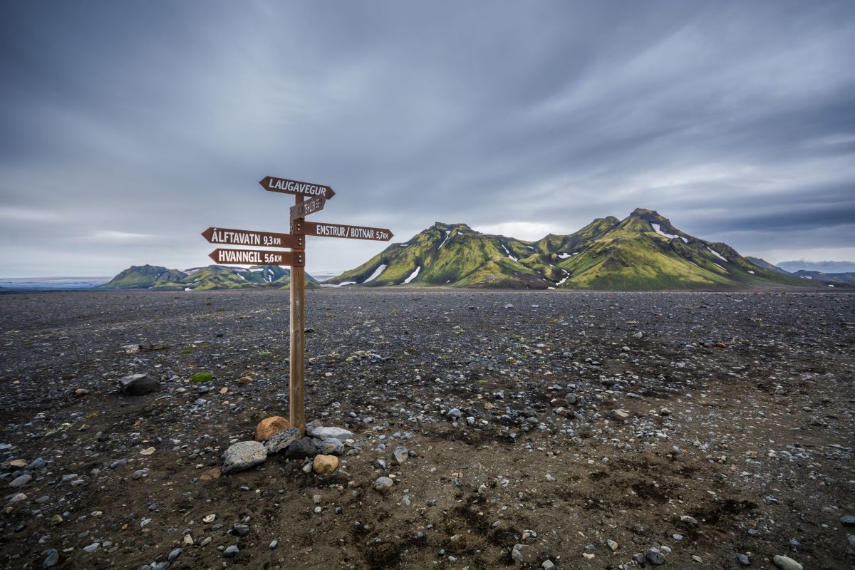 trail sign on black lava field with mountain background