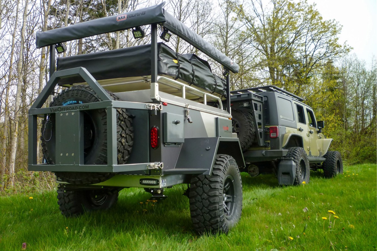 VMI Off Road Ox trailer with rooftop tent and awning mounted behind a Jeep in a grassy campsite