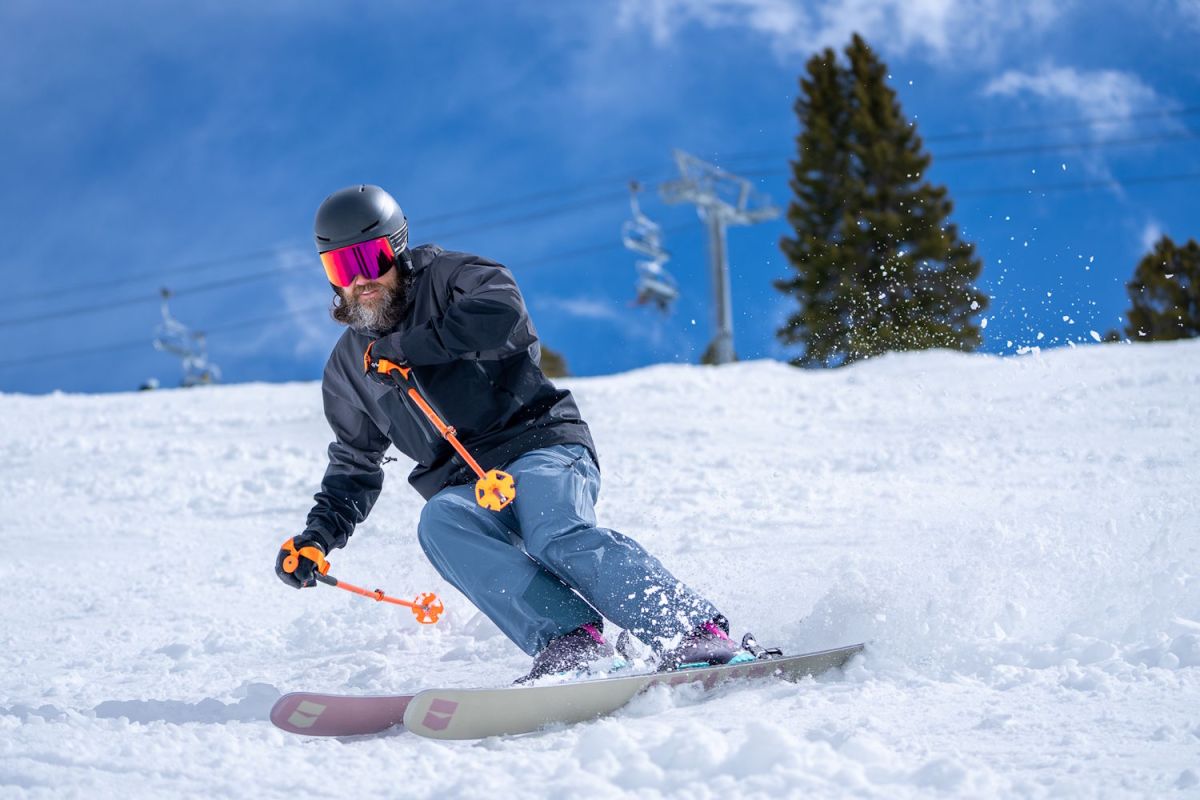 Skier carving a turn on a groomed slope wearing Rossignol AllTrack 130 Elite LV LT Ski Boots