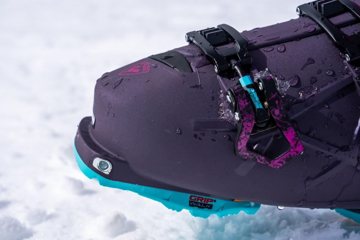 Close-up of pink and black Rossignol AllTrack 130 Elite LV LT ski boots standing in snow