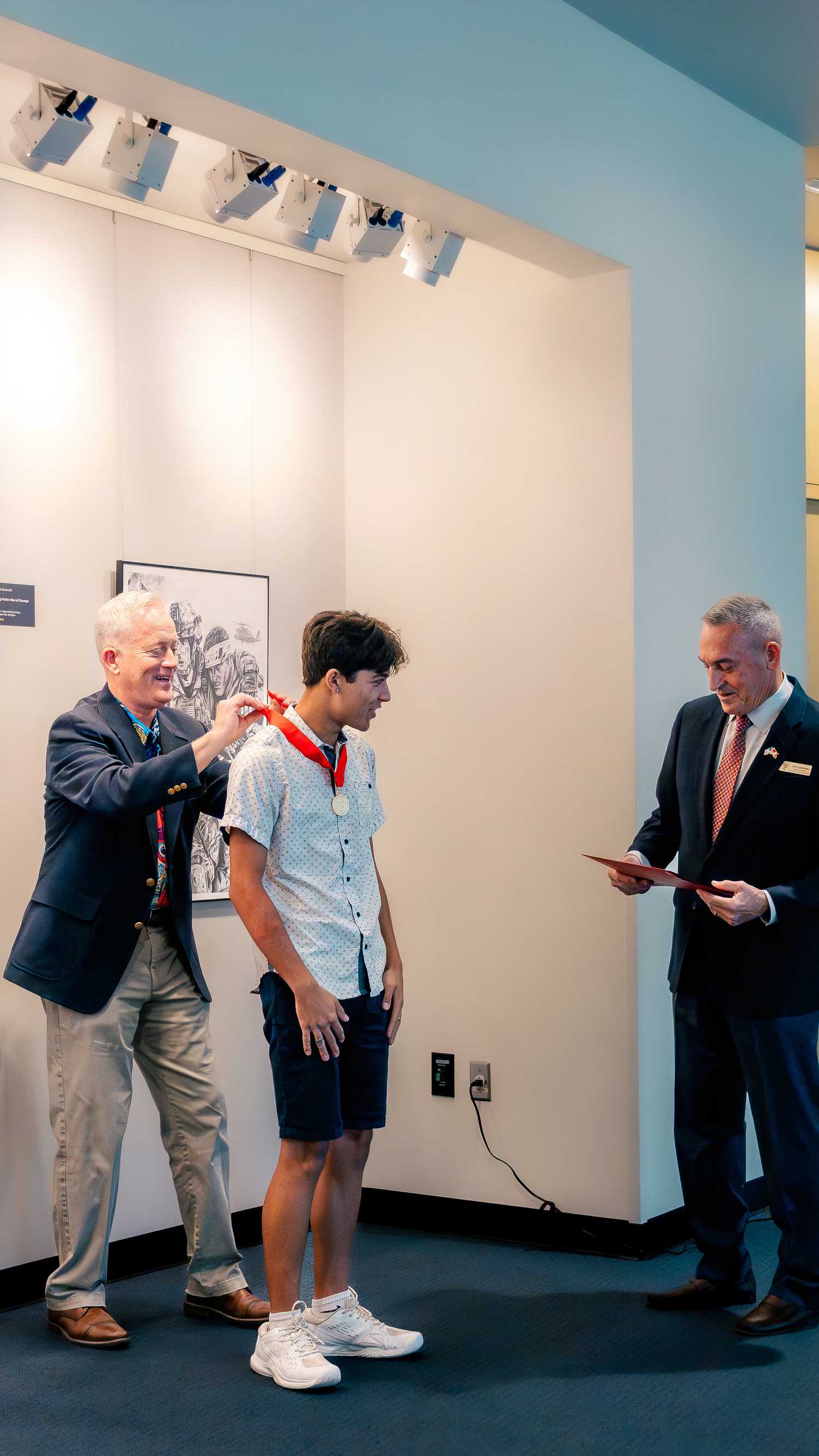 Marine Corps Artist in Residence Kris Battles presents an award to Woodbridge High School student Storm Alho during the Marine Corps Student Art Competition ceremony.
