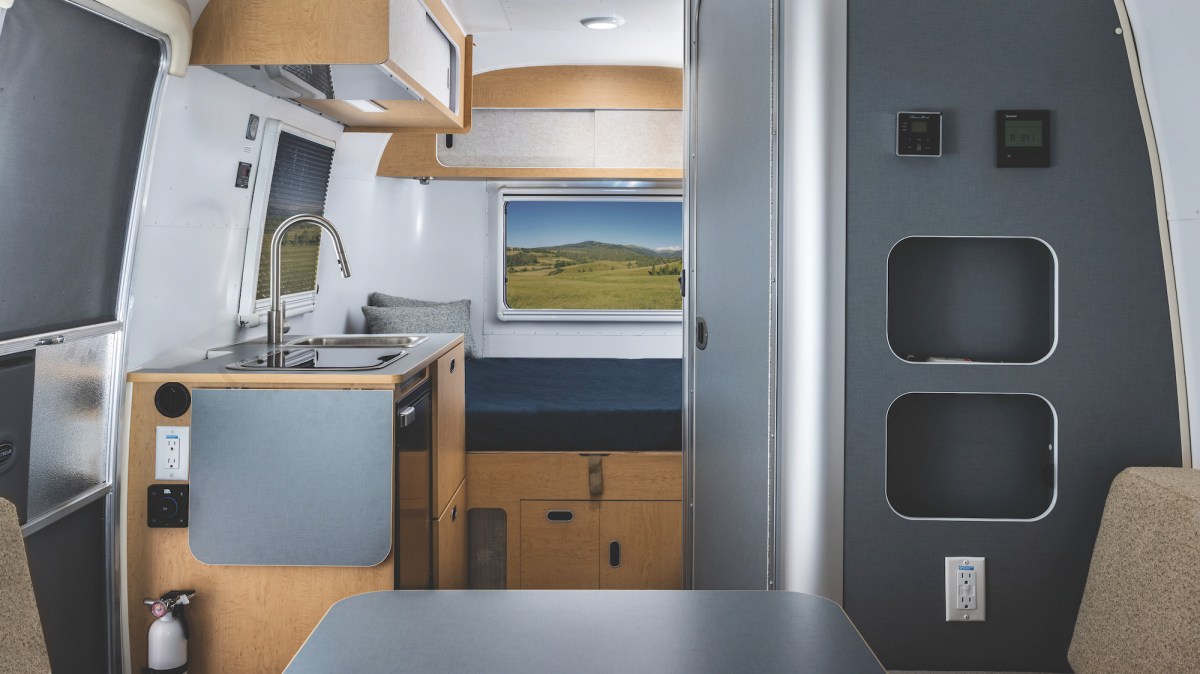 Interior view of an Airstream travel trailer with dark gray cabinets on the right and sink on the left.