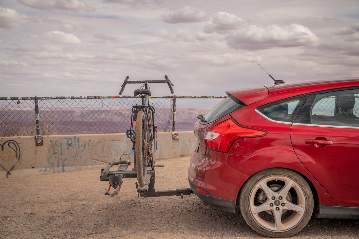 Bike on a Kuat NV 2.0 rack behind a red car at a canyon overlook