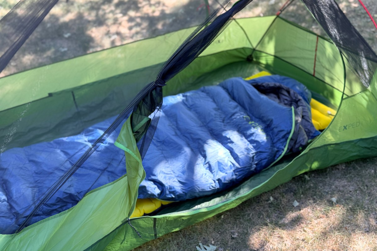 Inside view of a green Cassira tent with a blue sleeping bag and yellow sleeping pad set up under the mesh door