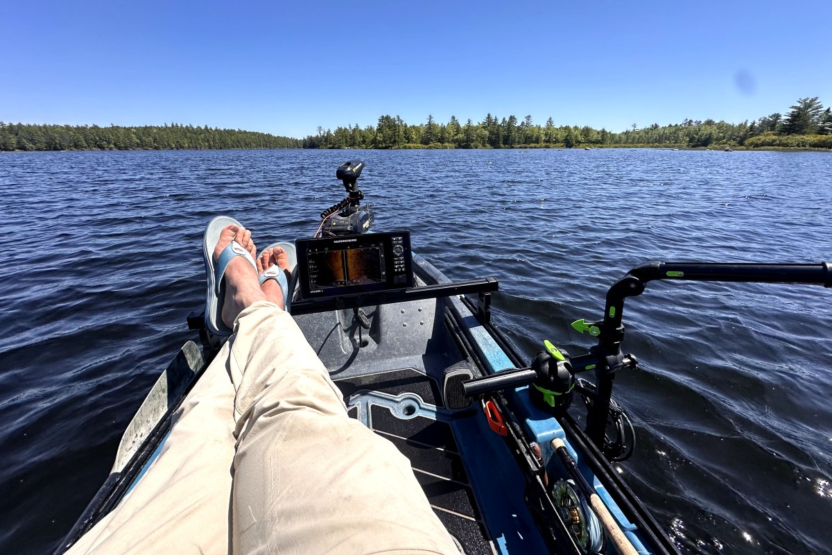 An anglers legs stretching out in a kayak cockpit.