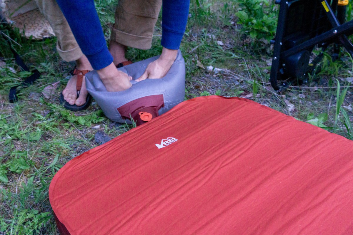 A camper uses the inflation sack to inflate the REI Co-op Westward Dreamer Camp Bed
