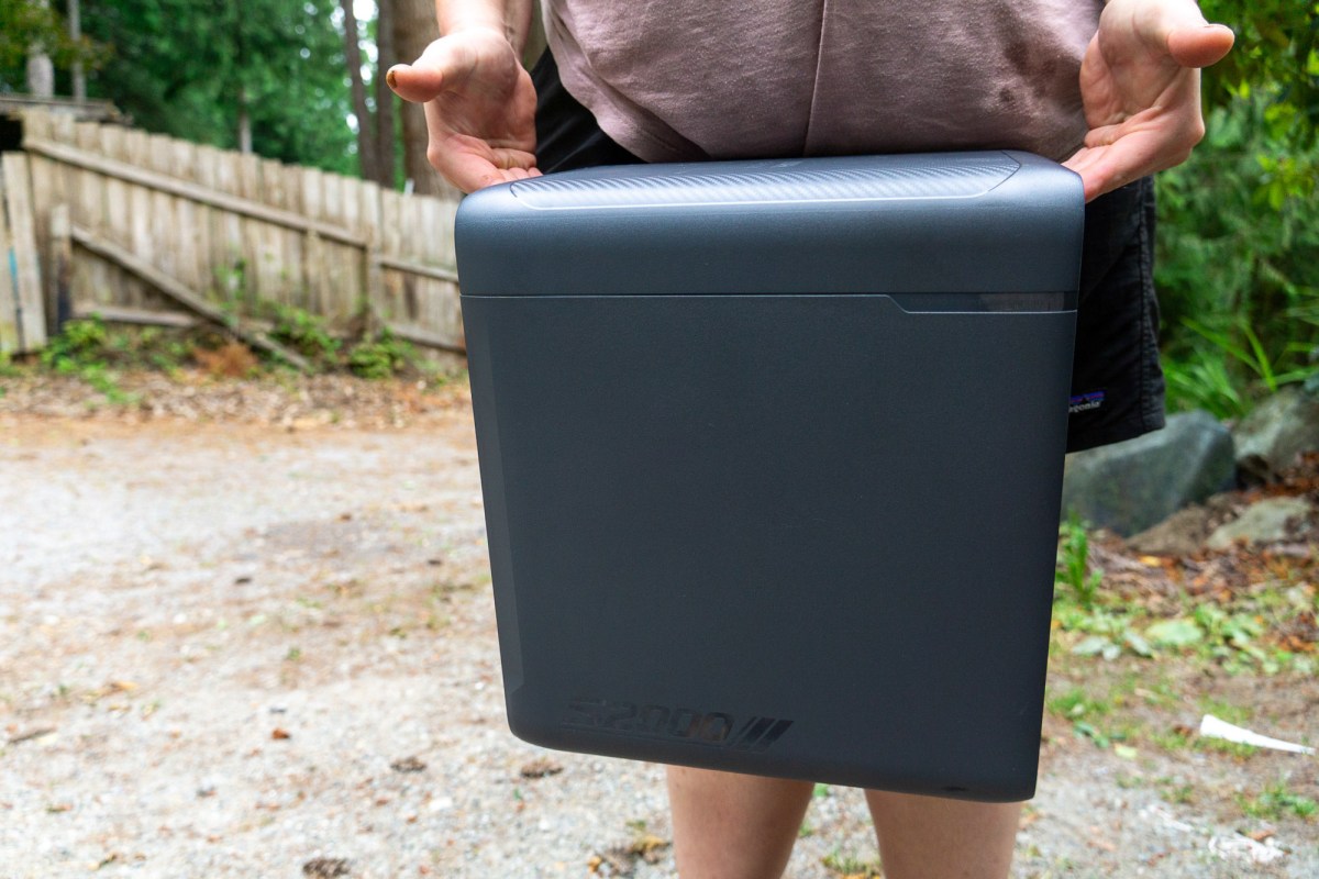 a woman holding the anker solix s2000 being the side handles outdoors