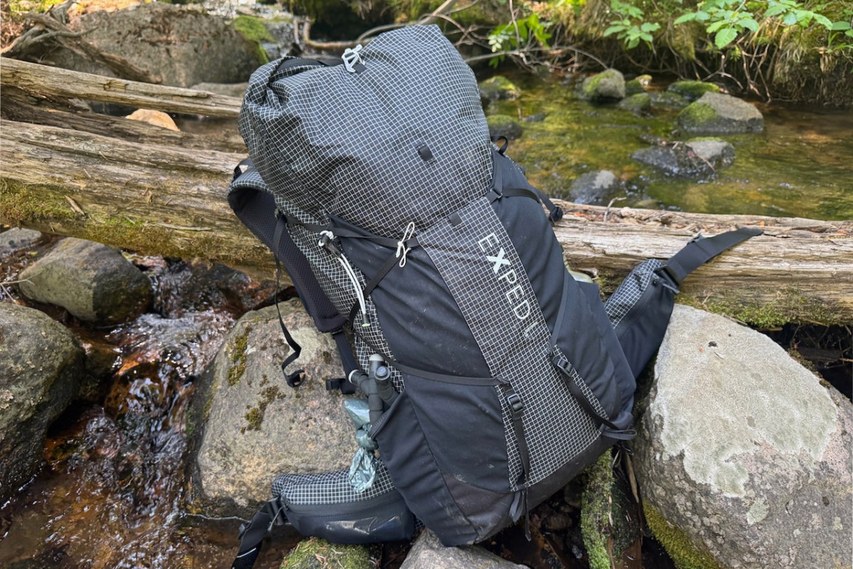 Exped Lightning 50 backpack resting on rocks beside a forest creek