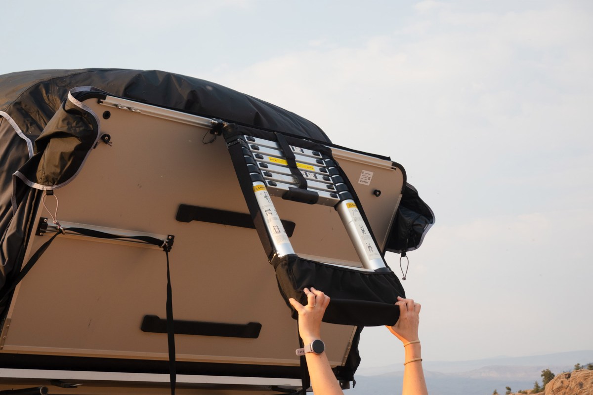 Hands folding the ladder beneath the iKamper rooftop camper platform